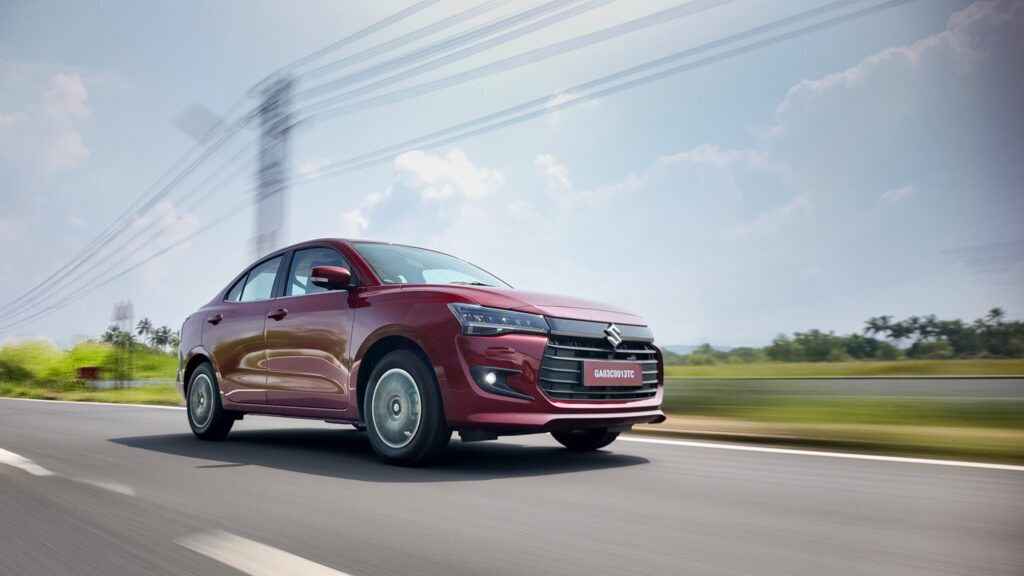 2025 Maruti Suzuki Dzire in motion showcasing sleek headlights, chrome grille, and modern body lines