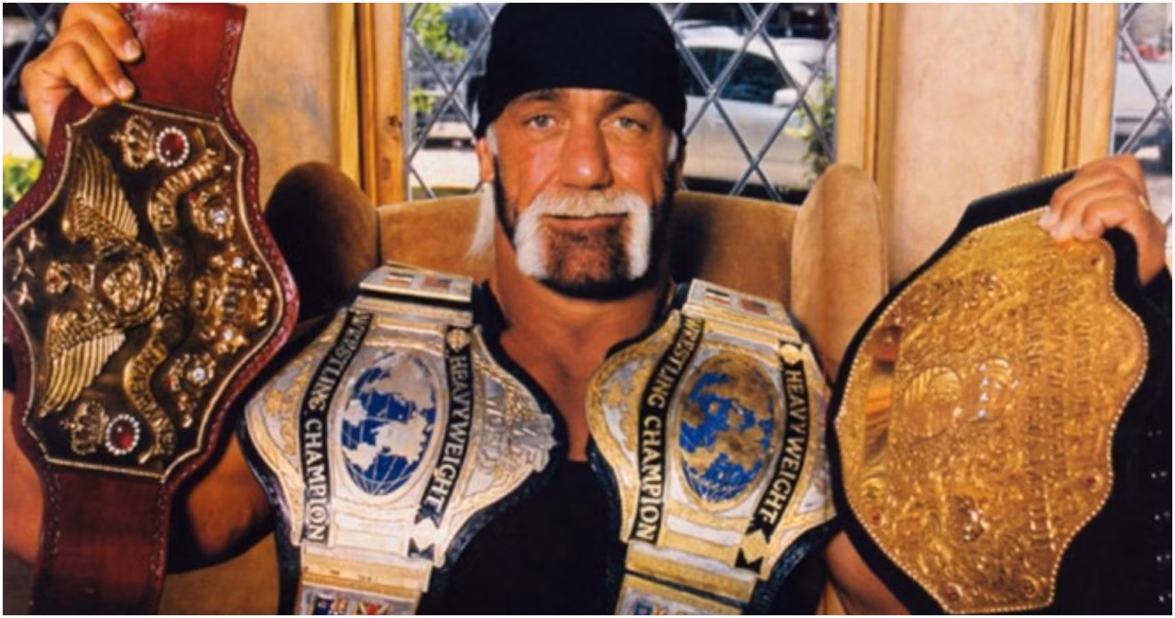 Hulk Hogan raises his championship belt high during a historic wrestling moment in the arena.